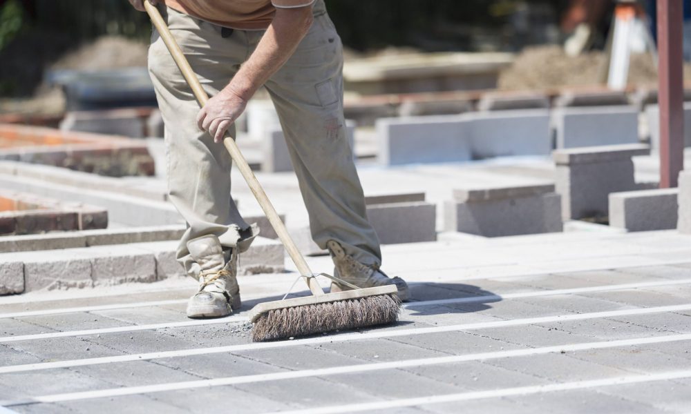 a-man-using-a-brush-on-a-cement-floor-on-a-constru-2023-11-27-05-28-18-utc